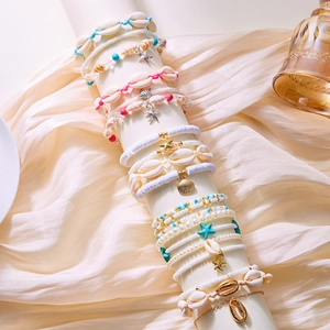 Detail of bohemian starfish and shell beaded anklets on a silk display stand
