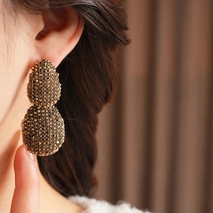 Primo piano di orecchini vintage a goccia con pavé di cristalli dorati su una modella