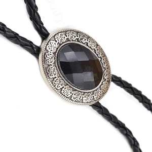Detailed close-up of a vintage silver bolo tie with black faceted gemstone and engraved motifs