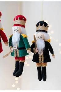 Close-up of festive fabric nutcracker soldier pendant with glitter details on light background