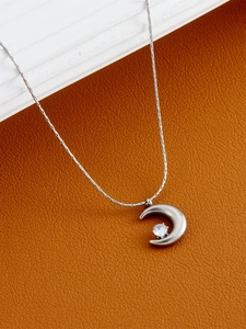 Close-up of crescent moon pendant necklace with zircon stone on a textured leather surface