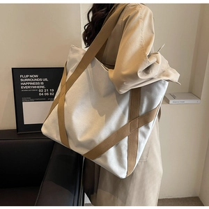 Detailed side view of a large capacity canvas tote bag with contrast straps for daily use
