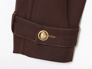 Detail of dark brown twill fabric sleeve with gold metal button and contrast yellow stitching