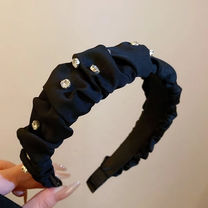 Detail of black pleated silk headband with sparkling rhinestones and elegant texture