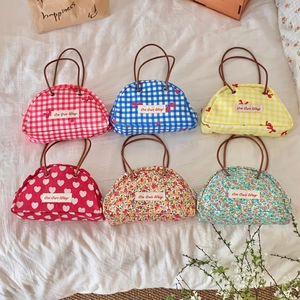 Collection of six semi-circle patterned canvas storage bags with brown handles on a bed
