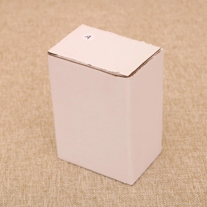 Close-up of white corrugated cardboard gift box with letter A sticker on hemp texture