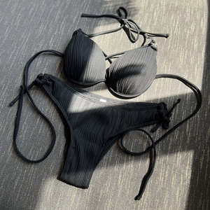 Detailed view of black ribbed bikini fabric with wired bra cups and side tie design