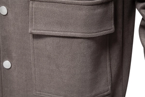 Détail d'une veste en daim pour homme avec une poche à rabat et un bouton en métal argenté