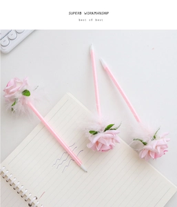 Detail of pink rose pens with white feathers and ballpoint tip on a minimalist notebook