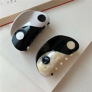 Close-up of yin yang pattern hair claws with marble texture and round polished finish