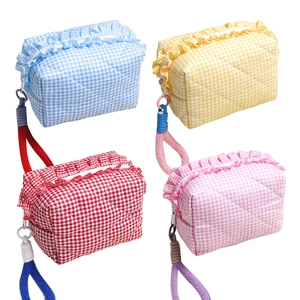 Quilted plaid makeup bags in blue, yellow, red, and pink with ruffle trim and knot handles