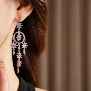 Close-up of elegant floral tassel earrings featuring purple crystals and silver finish