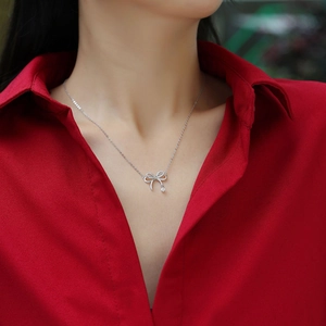 Close-up of S925 sterling silver bow pendant necklace with sparkling zircon on a model