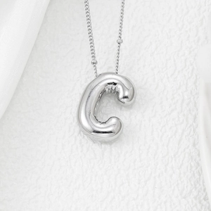 Macro shot of 3D puffy silver letter C balloon pendant on a fine O-chain necklace