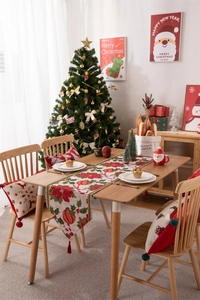 Dettaglio del runner da tavola natalizio e federa con stelle di Natale rosse e nappe