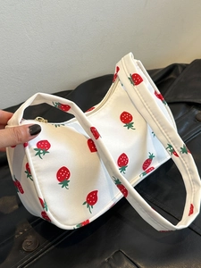 Detailed close-up of the red strawberry print on white nylon fabric of the handbag