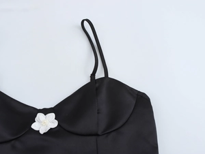 Detailed macro view of black satin bodice featuring a white 3D flower and heart neckline