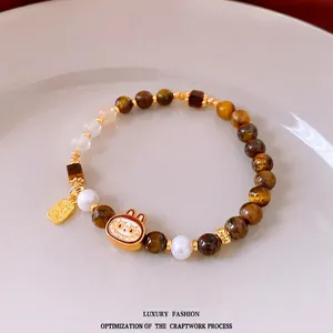 Bracciale di perle occhio di tigre con ciondolo tigre e targhetta Fu dorata su un piatto