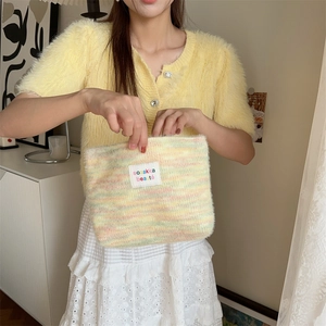 Macro detail of plush rainbow striped makeup bag featuring sozakka beaute label and soft texture
