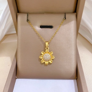 Close-up of golden sunflower pendant necklace with white diamonds in a jewelry box