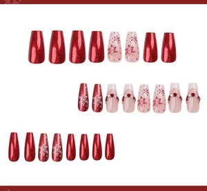 Detail view of long coffin nails with red glitter, snowflake prints and pearl rhinestones