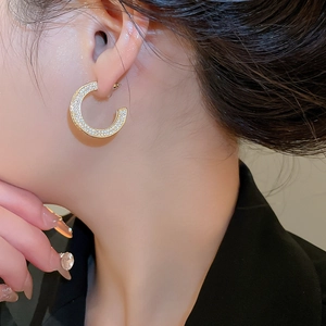 Close-up of elegant gold C-shaped earrings with shimmering cubic zirconia on model