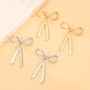 Detailed close-up of gold and silver bow-knot earrings with flowing ribbon design