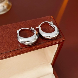 Close-up of silver U-shaped mirror finish earrings placed on a brown leather jewelry box