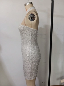 Detailed view of white bodycon dress with sparkling sequins and faux pearl embellishments