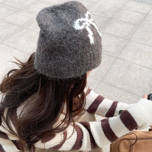 Detailed knit texture of dark grey beanie with a white plush bow accent on back