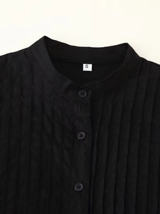 Detail of black pleated fabric and button-up mandarin collar on women's resort dress