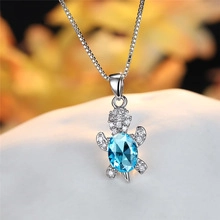 Macro shot of silver sea turtle pendant with a large oval blue crystal and white zircons