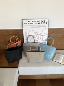 Detail of five assorted colorful woven straw tote bags displayed on a wooden bench