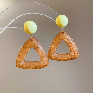 Detailed close-up of resin earrings with yellow circles and amber triangle pendants
