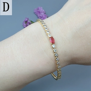 Detail view of gold bracelet with red oval zircon and micro-pave white stones