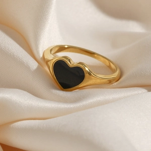 Close-up of gold plated stainless steel heart ring with black enamel on silk fabric