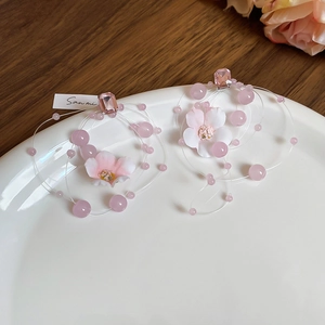 Detail of pink floral earrings with beads and crystal inside a white ceramic dish