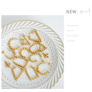Detail of vintage 18k gold plated U-shaped bead earrings on a white textured plate