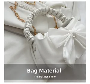 Detail of white pleated handbag featuring a large satin bow and golden chain strap