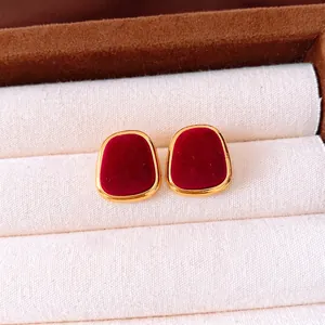 Vintage geometric flocking earrings in gold and deep red on a beige jewelry cushion