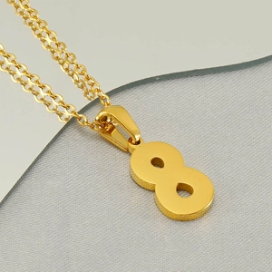 Macro view of gold stainless steel number 8 pendant necklace on textured grey fabric