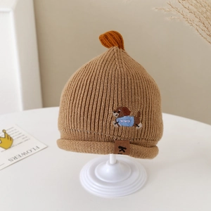 Détail d'un bonnet tricoté pour bébé avec broderie chien et étiquette en cuir K brun