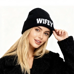 Détail de la broderie pelucheuse WIFEY blanche sur un bonnet en tricot noir d'hiver