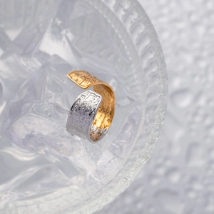 Detail shot of two-tone hammered gold and silver open ring placed on ice cubes