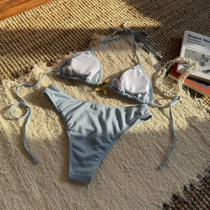 Detail of light blue glitter bikini with yellow star ornament on woven background