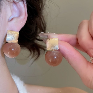 Close-up of vintage resin hoop earrings featuring gold square studs and amber spheres