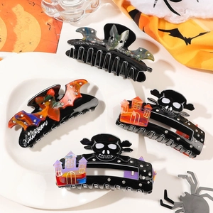 Halloween claw clips with bat and skull designs on a decorative tray