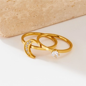 Minimalist gold moon and single diamond ring set displayed on a stone surface
