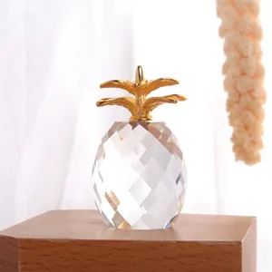 Modern crystal pineapple ornament with gold metal leaves on a natural wood display