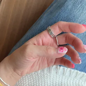 Detail of 925 sterling silver stacked rings featuring heart and flower embossed patterns